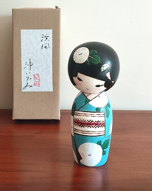 Hand-painted Kokeshi doll named Ryouhu, designed by artist Izumi, dressed in a blue kimono with morning glory flowers and a wind chime, symbolizing a cool Japanese summer breeze. Buy online at j-okini.com in Malta