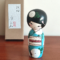 Hand-painted Kokeshi doll named Ryouhu, designed by artist Izumi, dressed in a blue kimono with morning glory flowers and a wind chime, symbolizing a cool Japanese summer breeze. Buy online at j-okini.com in Malta