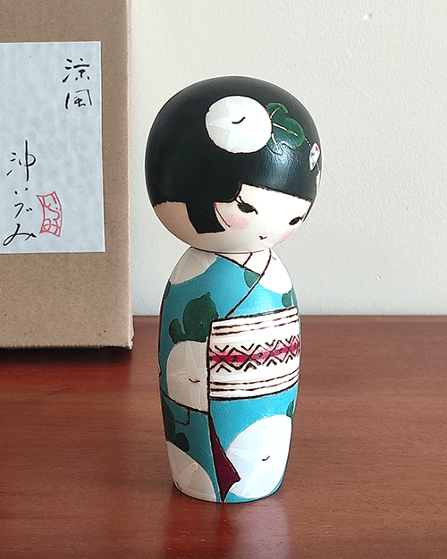 Hand-painted Kokeshi doll named Ryouhu, designed by artist Izumi, dressed in a blue kimono with morning glory flowers and a wind chime, symbolizing a cool Japanese summer breeze.