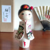Handcrafted Japanese Kokeshi doll 'Sakura Komachi' by artist Yamagishi Masayoshi, featuring a kanzashi hair bun and a kimono with hand-painted pink and blue cherry blossoms. Available at j-okini.com in Malta