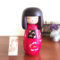 A modern Creative Kokeshi doll named ‘Benitsubaki,’ standing 17.5cm tall, wearing a bright red kimono with camellia flower motifs and a black obi. Available at j-okini.com in Malta Europe