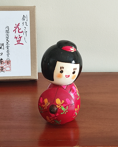 Kokeshi doll named Hanagasa holding an umbrella wearing red kimono. Made in Japan. Buy it online at j-okini.com in Malta