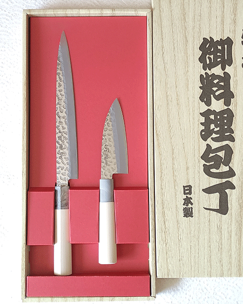 Gift masterpieces of Gifu and Seki of Japan. Yaxell is one of the major knife manufacturers in Japan since 1932, each Yaxell knife is a testament to the artistry and meticulous craftsmanship that has defined Japanese knife-making for generations, making them not just tools, but auspicious gifts that symbolize good fortune and prosperity. Made by Seki Tohei, and there are sign of 関藤平 on each knife. Blade It features a striking hammered design and provides comfortable cutting. Handle Sculpted from natural wood, designed to harmonize with your grip over time, becoming an extension of your culinary expression. This natural material not only adds to the knife's aesthetic but ensures durability and comfort with every use. This gift set includes: 1. 刺身包丁 Sashimi Bocho Overall length 330mm Blade length 205mm Weight: 79g Designed for precision, the Sashimi Bocho is the epitome of Japanese culinary artistry. Its long, slender blade is crafted to execute the most delicate and thin slices, perfect for sashimi, showcasing the knife's blend of functionality and elegance. 2.小出刃包丁 Small deba bocho Overall length 220mm Blade length 105mm Weight: 44g Specialized for handling smaller fish, this knife combines robustness and precision. Its compact design and sharp edge make it ideal for detailed work, from filleting to intricate cuts, embodying the spirit of traditional Japanese fish preparation.. Available at j-okini.com Malta