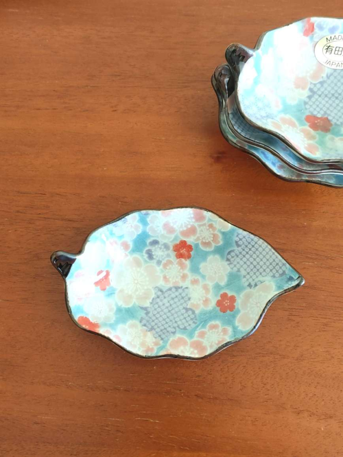 Aritaware Small Porcelain Leaf Plate with Sakura Design With a history dating back to the 4th century, Aritaware represents centuries of Japanese craftsmanship and tradition. Each piece reflects the skill and artistry of master craftsmen, beautifully preserved for the present. This elegant leaf-shaped porcelain plate features a delicate sakura (cherry blossom) design in light blue, making it both charming and versatile. Perfect as a soy sauce dish, for serving condiments, or even as a stylish holder for accessories on your bedroom dresser. Made in Japan, this plate embodies timeless artistry and functionality. Available at j-okini.com in Malta