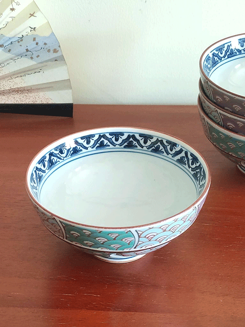 Handcrafted in the famed pottery region of Arita, Japan, the rice bowl features a stunning 青海波 (Seigaiha) wave pattern in shades of green and purple, elegantly traced with gold accents.  The rim is adorned with intricate navy blue detailing, enhancing the bowl’s overall sophistication. Available at j-okini.com in Malta