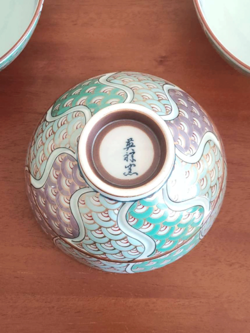 This exquisite Japanese rice bowl exemplifies the rich, over 400-year tradition of Arita ware, renowned for its timeless beauty and expert craftsmanship. Handcrafted in the famed pottery region of Arita, Japan, the bowl features a stunning 青海波 (Seigaiha) wave pattern in shades of green and purple, elegantly traced with gold accents.  The rim is adorned with intricate navy blue detailing, enhancing the bowl’s overall sophistication. Each bowl is meticulously hand-painted, showcasing the artistry and skill of the craftsmen who continue to honor Arita's proud ceramic heritage. Its versatile size makes it ideal for serving rice, soups, or even desserts, adding a refined touch to any meal. Made in Japan What is the Seigaiha Pattern? The 青海波 (Seigaiha), or "blue ocean wave" pattern, is a traditional Japanese motif symbolizing the calm and endless waves of the sea. This auspicious design is believed to represent a wish for a peaceful and prosperous life. Available at j-okini in Malta