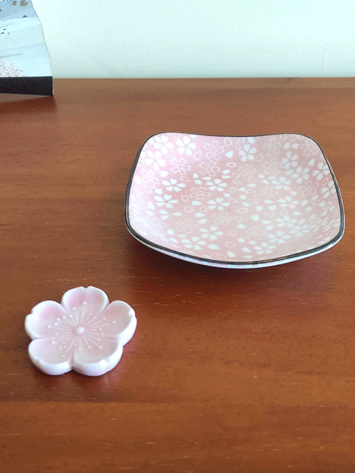 This charming set features a light pink Sakura plate paired with a matching Sakura-shaped chopstick rest. The square plate, adorned with delicate cherry blossom (Sakura) patterns, has a slight depth, making it perfect for serving soy sauce or small side dishes. Both pieces are crafted in the Mino ware (Mino-yaki) tradition, a celebrated Japanese pottery style known for its beautiful and functional designs. Available at j-okini.com in Malta