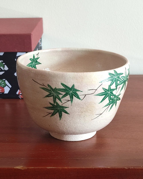 Kiyomizu-ware Matcha bowl with green maple leaves design on a warm beige background, inspired by Japanese summer landscapes. Available at j-okini.com in Malta