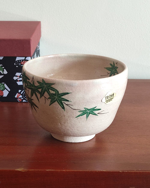 Kiyomizu-ware Matcha bowl with green maple leaves design on a warm beige background, inspired by Japanese summer landscapes. Available at j-okini.com in Malta