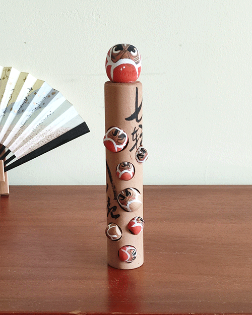 Vintage wooden Daruma doll with seven smaller Daruma figures, inscribed with the proverb 'Nanakorobi Yaoki' for resilience, stamped from Kawayu Onsen area, 17.5 cm tall with craftsman's mark. Available at j-okini.com in Malta