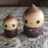 A pair of vintage wooden dolls shaped like acorns, with removable tops representing the acorn heads. The dolls show signs of age with slight scratches. One is larger, measuring approximately H10 x W6.5cm, and the smaller one is H6.5 x W4cm. These unique pieces come from a personal collection in Japan, tied to Mount Daisen in Tottori Prefecture.. Available at j-okini.com in Malta