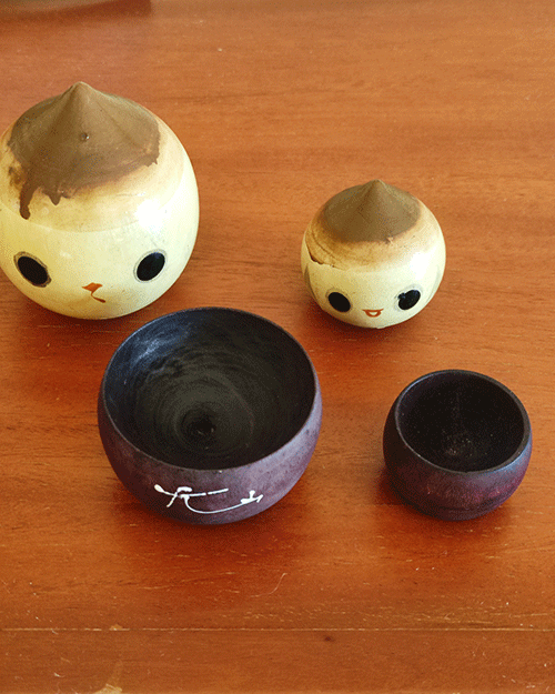 A pair of vintage wooden dolls shaped like acorns, with removable tops representing the acorn heads. The dolls show signs of age with slight scratches. One is larger, measuring approximately H10 x W6.5cm, and the smaller one is H6.5 x W4cm. These unique pieces come from a personal collection in Japan, tied to Mount Daisen in Tottori Prefecture.. Available at j-okini.com in Malta