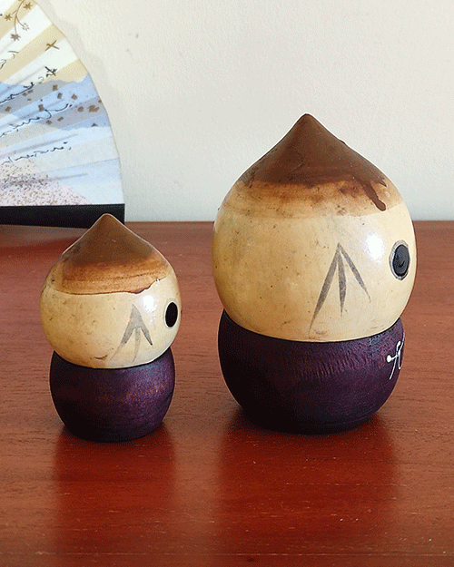 A pair of vintage wooden dolls shaped like acorns, with removable tops representing the acorn heads. The dolls show signs of age with slight scratches. One is larger, measuring approximately H10 x W6.5cm, and the smaller one is H6.5 x W4cm. These unique pieces come from a personal collection in Japan, tied to Mount Daisen in Tottori Prefecture.. Available at j-okini.com in Malta