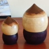 A pair of vintage wooden dolls shaped like acorns, with removable tops representing the acorn heads. The dolls show signs of age with slight scratches. One is larger, measuring approximately H10 x W6.5cm, and the smaller one is H6.5 x W4cm. These unique pieces come from a personal collection in Japan, tied to Mount Daisen in Tottori Prefecture.. Available at j-okini.com in Malta