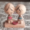 A pair of vintage wooden dolls from Izumo Taisha Shrine in Seiza position, representing a boy and girl. Hand-painted with traditional kimonos and seated with a red sake cup inscribed with "寿" (kotobuki). A faint craftsman's stamp is next to the girl on the wooden base. Available at j-okini.com in Malta