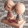 A pair of vintage wooden dolls from Izumo Taisha Shrine in Seiza position, representing a boy and girl. Hand-painted with traditional kimonos and seated with a red sake cup inscribed with "寿" (kotobuki). A faint craftsman's stamp is next to the girl on the wooden base.