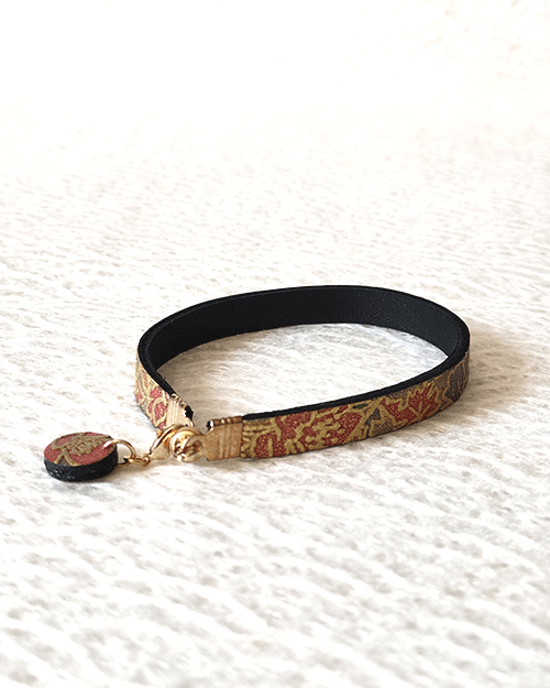 Floral Mist handmade leather bracelet with a light grey base and pink, purple, and green floral pattern, traced in gold, with a matching charm and magnetic clasp