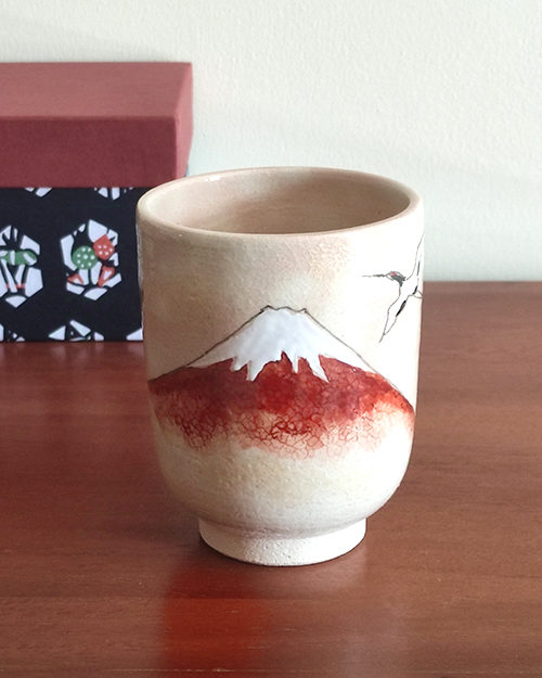 Kiyomizu-ware Yunomi tea cup featuring Red Fuji and crane design on a warm beige base with subtle orange-pink flecks. Available at j-okini.com in Malta