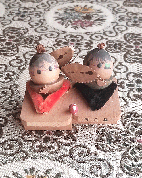 Vintage Wooden Dolls from the Showa Era. A pair of donguri dolls seated on wooden geta sandals, featuring hand-painted details and a mushroom accent.. Available at j-okini.com in Malta