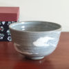 Kiyomizu-ware handmade matcha bowl with Hakeme brushstroke technique on a gray base, with white strokes and hints of light blue by artist Hiroki Shirai. j-okini.com in Malta