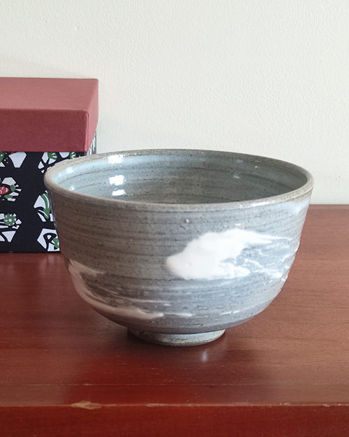 Kiyomizu-ware handmade matcha bowl with Hakeme brushstroke technique on a gray base, with white strokes and hints of light blue by artist Hiroki Shirai. j-okini.com in Malta