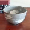 Kiyomizu-ware handmade matcha bowl with Hakeme brushstroke technique on a gray base, with white strokes and hints of light blue by artist Hiroki Shirai. j-okini.com in Malta