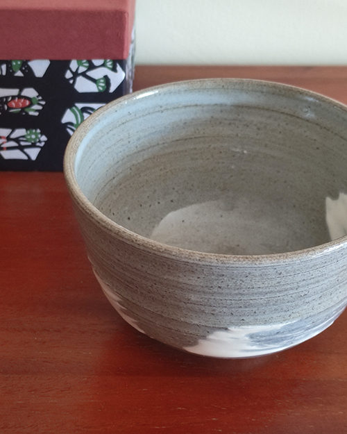 Kiyomizu-ware handmade matcha bowl with Hakeme brushstroke technique on a gray base, with white strokes and hints of light blue by artist Hiroki Shirai. j-okini.com in Malta