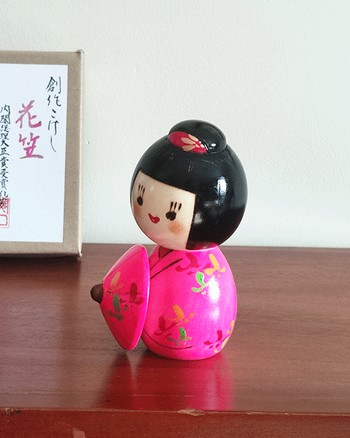 Kokeshi doll named Hanagasa by Sekiguchi Toua, wearing vivid pink kimono and holding an umbrella. j-okini.com in Malta