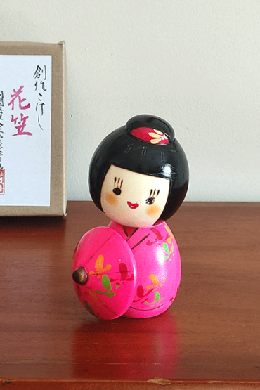 Kokeshi doll named Hanagasa by Sekiguchi Toua, wearing vivid pink kimono and holding an umbrella. j-okini.com in Malta