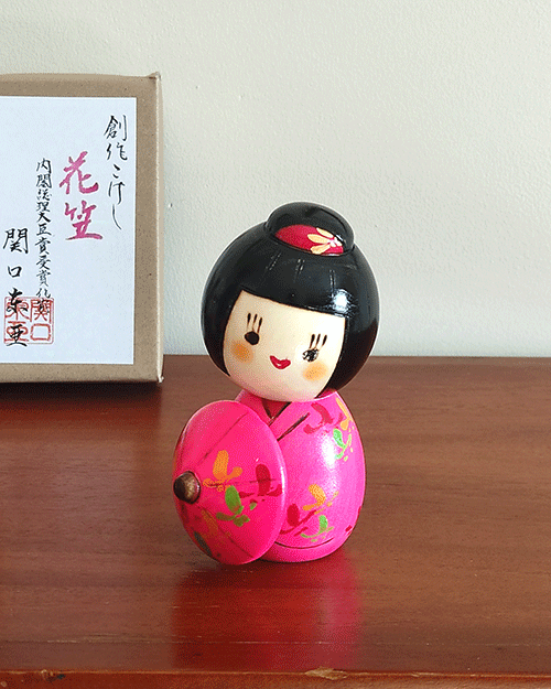 Kokeshi doll named Hanagasa by Sekiguchi Toua, wearing vivid pink kimono and holding an umbrella. j-okini.com in Malta