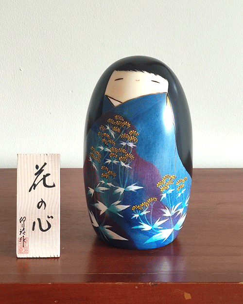 Handcrafted Kokeshi doll named Hana no Kokoro,by Usaburo adorned with floral patterns, symbolizing a heart of flowers and expressing grace and beauty in Japanese artistry.. Buy it online at j-okini.com in Malta