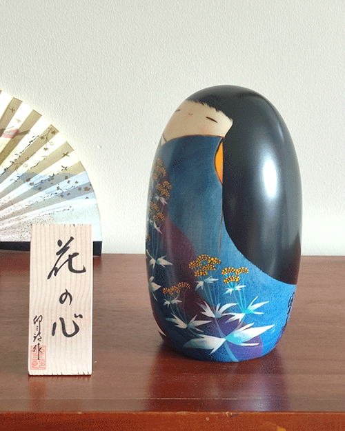 Handcrafted Kokeshi doll named Hana no Kokoro,by Usaburo adorned with floral patterns, symbolizing a heart of flowers and expressing grace and beauty in Japanese artistry.. Buy it online at j-okini.com in Malta