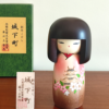 Kokeshi doll named Jokamachi featuring a beautiful depiction of a castle and delicate cherry blossoms on a soft pink kimono, symbolizing the elegance and history of Japanese heritage.. Buy it online at j-okini.com in Malta