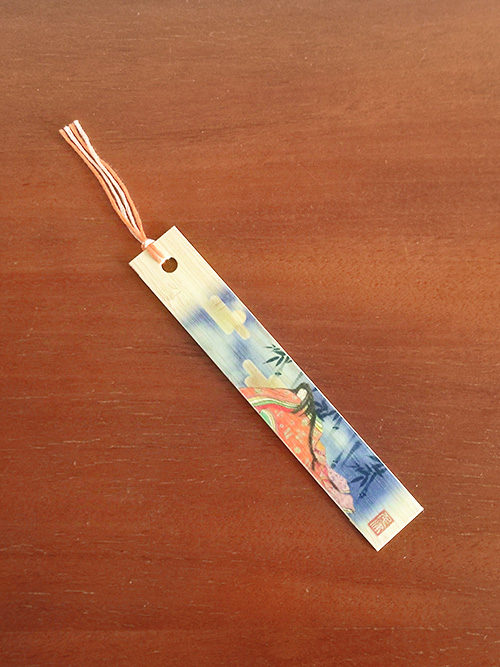 Handcrafted bamboo bookmark featuring Kaguyahime from The Tale of the Bamboo Cutter, with unique colored thread and '竹しおり' (bamboo bookmark) written on the back. j-okini.com in Malta