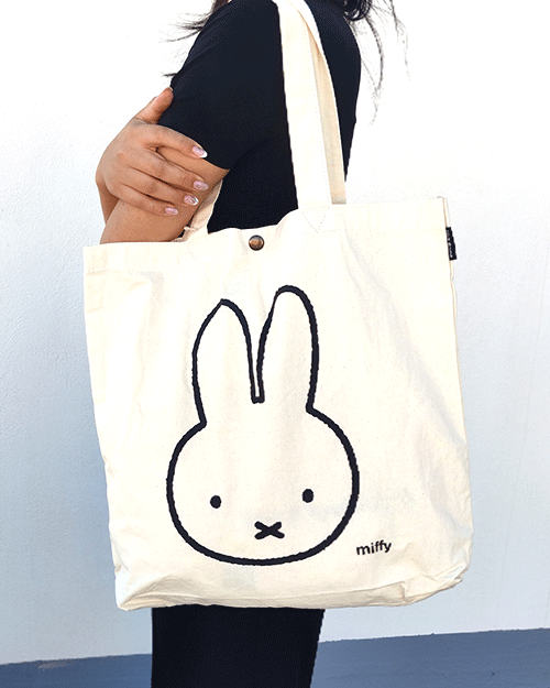 Miffy's slim canvas tote bag in white with a large Miffy illustration in black. button closure tote bag. Spacious tote bag. Japanese tote bag. Availabe at j-okini.com in Malta