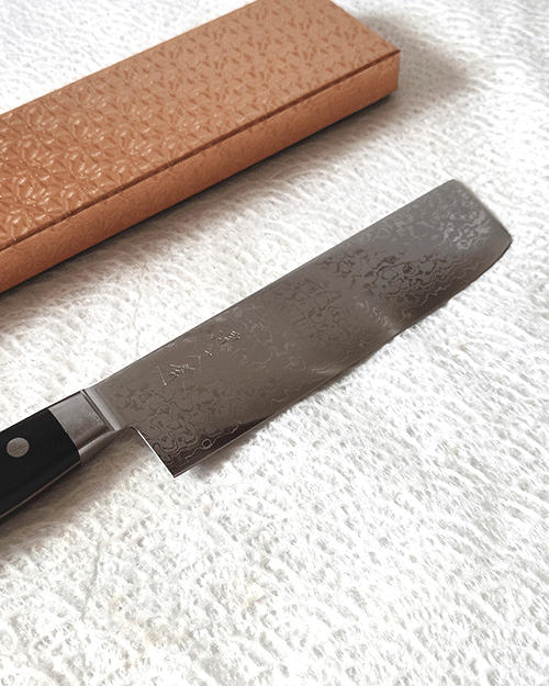 Japanese Nakiri kitchen knife with VG10 core, 16-layer Damascus wave pattern, and a rectangular shape, ideal for precise vegetable slicing and chopping.. Buy it from j-oini in Malta