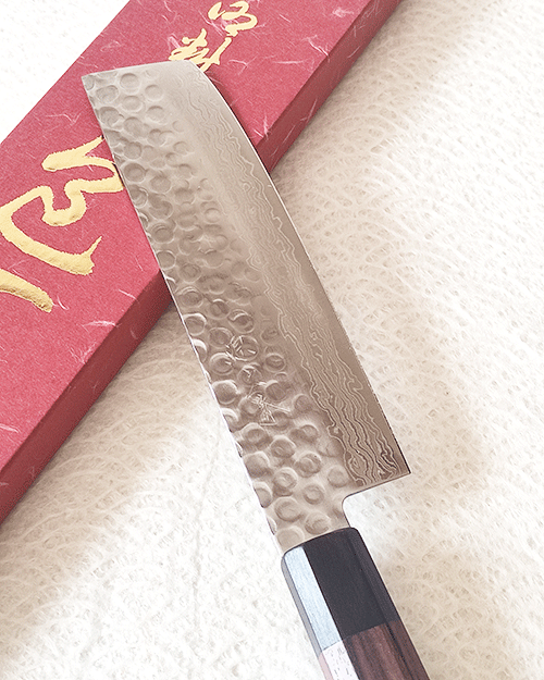 Handcrafted Japanese Nakiri kitchen knife with a hammered and wave-patterned AUS10 stainless steel blade, octagonal rosewood handle, and traditional craftsmanship. Available at j-okini in Malta