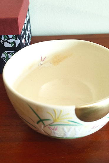 Kiyomizu-ware handmade matcha bowl with Otsukimi moon-viewing design, featuring six rabbits beneath a golden full moon on a cream background, with detailed gold accents on the grasses and rabbits. j-okini.com in Malta