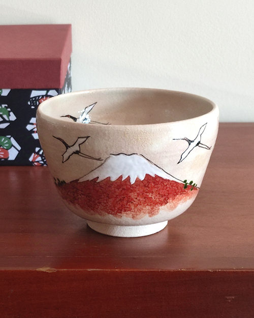 Handcrafted Kiyomizu-ware Matcha bowl featuring Red Fuji and crane design on a warm beige background with soft pink and orange speckles.. Gift idea from j-okini.com in Malta