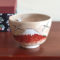 Handcrafted Kiyomizu-ware Matcha bowl featuring Red Fuji and crane design on a warm beige background with soft pink and orange speckles.. Gift idea from j-okini.com in Malta