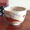 Handcrafted Kiyomizu-ware Matcha bowl featuring Red Fuji and crane design on a warm beige background with soft pink and orange speckles.. Gift idea from j-okini.com in Malta