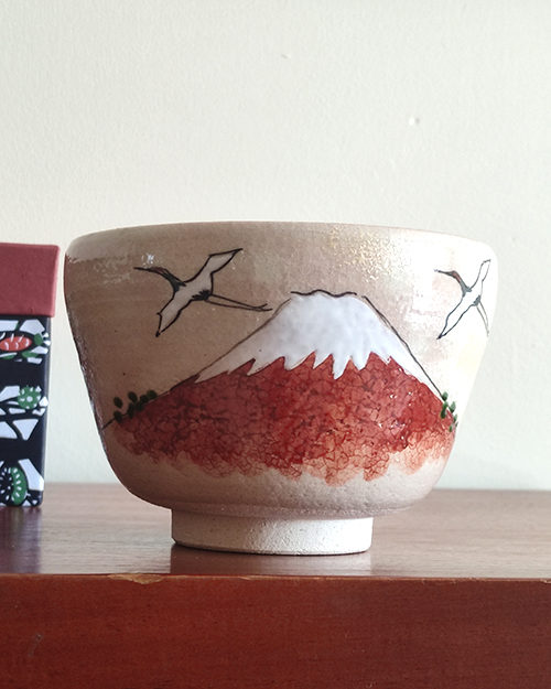 Handcrafted Kiyomizu-ware Matcha bowl featuring Red Fuji and crane design on a warm beige background with soft pink and orange speckles.. Gift idea from j-okini.com in Malta