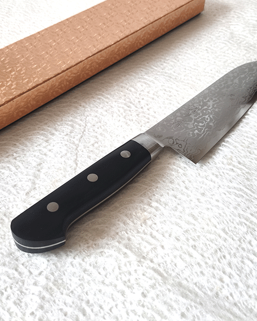 Japanese Santoku kitchen knife with a VG10 Damascus blade featuring a unique wave pattern and an elegant, simple handle. buy it at j-okini.com in Malta