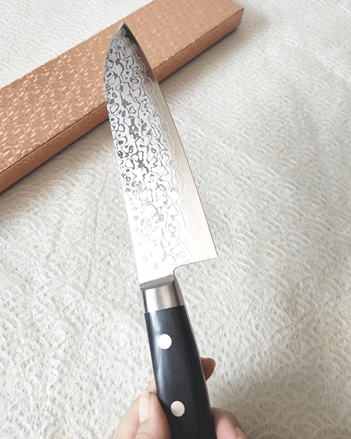 Japanese Santoku kitchen knife with a VG10 Damascus blade featuring a unique wave pattern and an elegant, simple handle. buy it at j-okini.com in Malta