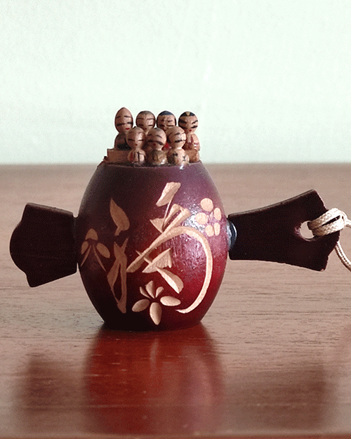 Vintage miniature Shichifukujin wooden doll on Tsutsumi from the Showa era. Features seven hand-painted lucky gods on a carved Tsutsumi with a 福 'luck' kanji and floral design. Available at j-okini.com in malta