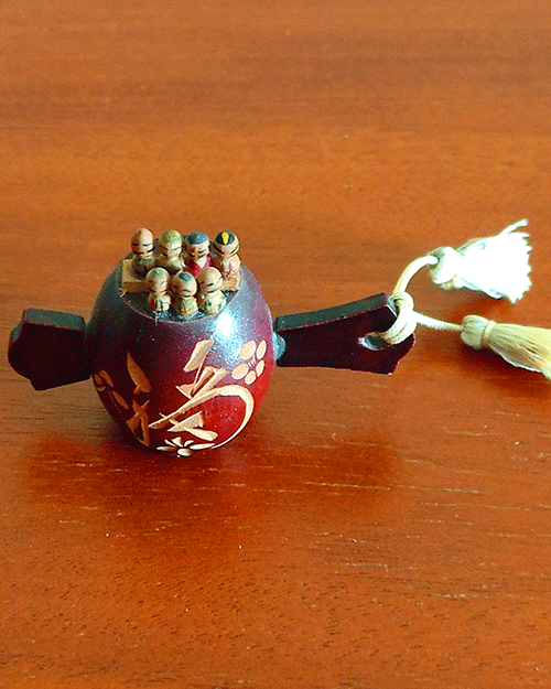 Antique miniature Shichifukujin wooden doll on Tsutsumi from the Showa era. Features seven hand-painted lucky gods on a carved Tsutsumi with a 福 'luck' kanji and floral design. Available at j-okini.com in malta