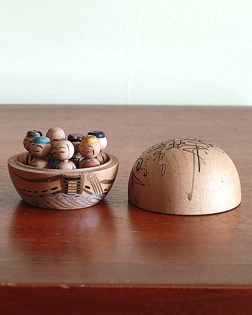 Vintage miniature wooden Shichifukujin doll set on a hand-painted boat with removable calligraphy lid, showing the Seven Lucky Gods with turnable heads. Antique Japan.