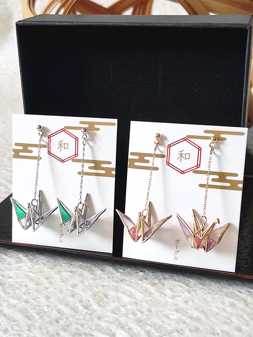 These earrings are designed in the shape of origami cranes, beautifully colored to resemble stained glass. Available in two enchanting color options: Gold: Featuring pink and purple crane wings Silver: Showcasing green and purple crane wings The charming crane design not only adds a cute and stylish touch but also carries the auspicious symbolism of peace, making these earrings both meaningful and elegant Available at j-okini.com in Malta