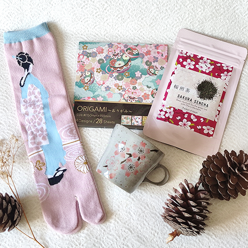 Cherry blossom-themed gift box with Sakura sencha tea, pink or purple Sakura Seiji mug, sakura-pattern origami, and Maiko-themed Tabi socks, packaged in a craft box. Perfect Japanese gift set with customizable options. j-okini.com in Malta