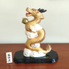 A golden dragon figurine standing 19cm tall, depicted soaring into the sky amidst white clouds, holding a "Hoju" (sacred jewel) in its claw. The dragon's dynamic pose symbolizes prosperity and improved luck, while the black lacquered base adds a touch of elegance. Gift idea from j-okini.com in Malta